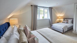 Une chambre avec deux lits, une fenêtre avec des rideaux, une lampe et une table de chevet.
