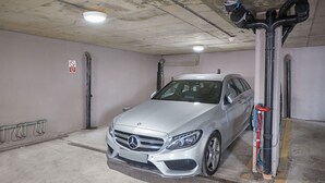 Hopeanvärinen Mercedes-Benz oli pysäköitynä betoniseinäiseen autohalliin, jonka katossa oli näkyvillä putkia ja jossa oli kyltti, jossa luki: «Pysäköinti kielletty».