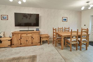 Una sala de estar con un televisor de pantalla plana grande, muebles de madera y piso alfombrado.