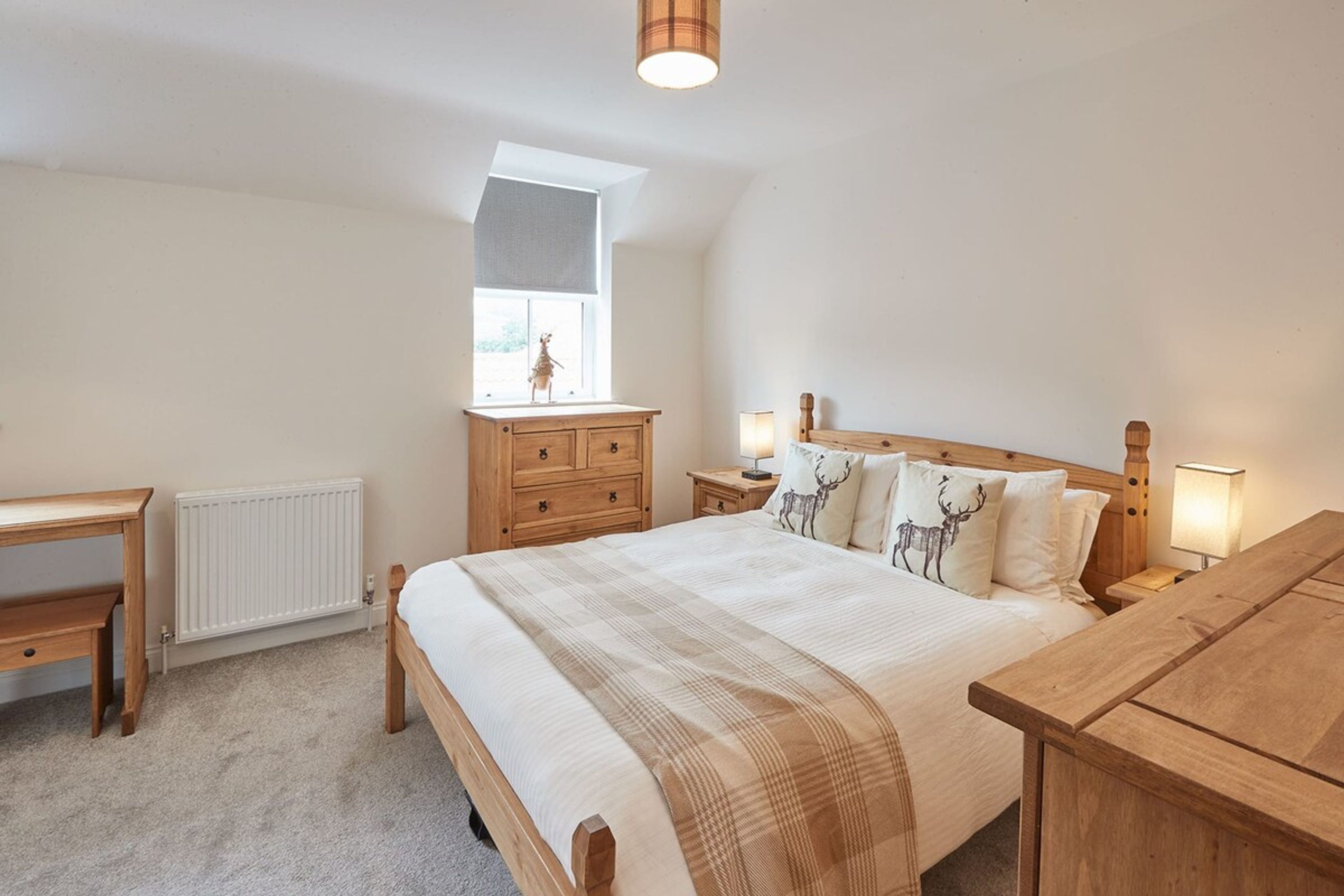 A bedroom with a large bed, wooden furniture, a window, and a radiator.