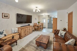 A living room with a TV, wooden furniture, a coffee table, and a sofa.