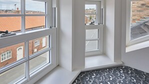 Een kamer met grote ramen, uitzicht op gebouwen en een vloer met een patroon.