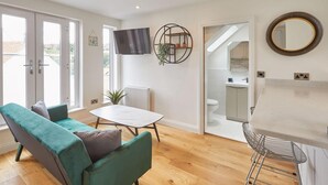 Een moderne woonkamer met een bank, een tafel en een aan de muur bevestigde televisie.