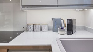 A modern kitchen with a built-in stove, a kettle, and a coffee maker on the countertop. - Host Stay Staffordshire Hideaway (Whitby)