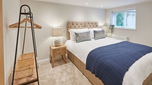 A bedroom with a bed, bedside tables, a hanging rack, and a window with blinds. - Host Stay Staffordshire Hideaway (Whitby)