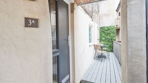 A narrow outdoor corridor with a wooden ceiling, a small table with chairs, and a green hedge in the background. - Host Stay Staffordshire Hideaway (Whitby)