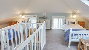 A bedroom with two beds, a crib, and a radiator. - Host Stay Tenby Cottage (Whitby)