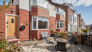 A residential property with a front garden, a wooden door, a mailbox, a bench, and a table with chairs. - Host Stay Tenby Cottage (Whitby)