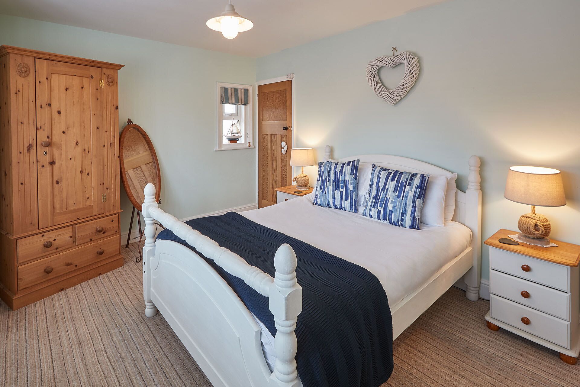 A bedroom with a bed, wooden wardrobe, bedside tables, and a wall decoration.