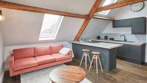 Un appartement de style « loft » comprenant une cuisine, un canapé, une table basse et une horloge murale.