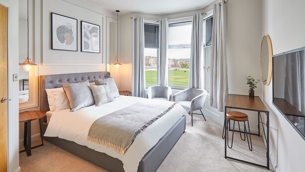 Une chambre moderne avec un grand lit, des tables de chevet, un bureau et un téléviseur.