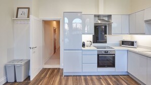 Une cuisine moderne avec des meubles blancs, un four à micro-ondes, un four traditionnel et un évier.