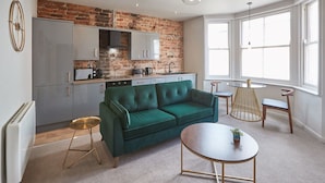 Una cocina moderna con pared de ladrillo, un sofá verde y una mesa de comedor redonda.