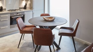 Una cocina moderna con una mesa redonda y cuatro sillas de cuero.