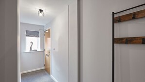 Un pasillo con una puerta de madera, una lámpara en el techo y una ventana decorada con un mural de cebra.