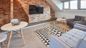 Un salon moderne avec un mur en briques, un téléviseur à écran plat, un canapé, une table basse et un tapis à motifs.