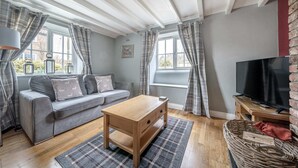 A cozy living room with a grey sofa, wooden coffee table, and a television on a wooden stand. - Host Stay Great Habton Cottage (Malton)