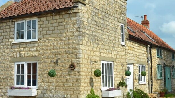 A stone building with a red-tiled roof, multiple windows, and potted plants. - Host Stay Great Habton Cottage (Malton)