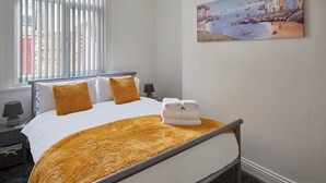 A hotel room with a bed, a painting of a coastal scene, and a window with blinds. - Host Stay Diamond One (Saltburn-by-the-Sea)