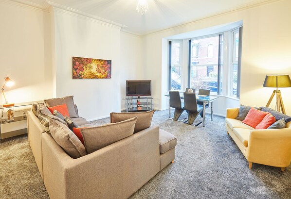 Relax in this stylish living room with a beige sofa, armchair, and flat-screen TV.