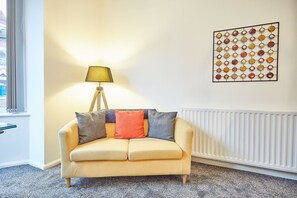 A living room with a sofa, a lamp, and a wall art piece. - Host Stay Diamond One (Saltburn-by-the-Sea)