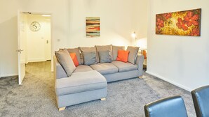 A living room with a grey sofa, a clock, and two paintings on the wall. - Host Stay Diamond One (Saltburn-by-the-Sea)