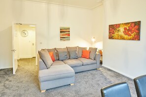 Relax in this stylish living room with a comfortable sofa, colorful artwork, and a clock on the wall.