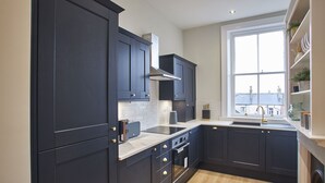 Une cuisine moderne avec des meubles de couleur sombre, une grande fenêtre et une vue sur la ville.
