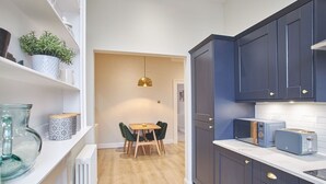Une cuisine moderne avec des meubles de couleur sombre, une table à manger en bois et un luminaire suspendu.
