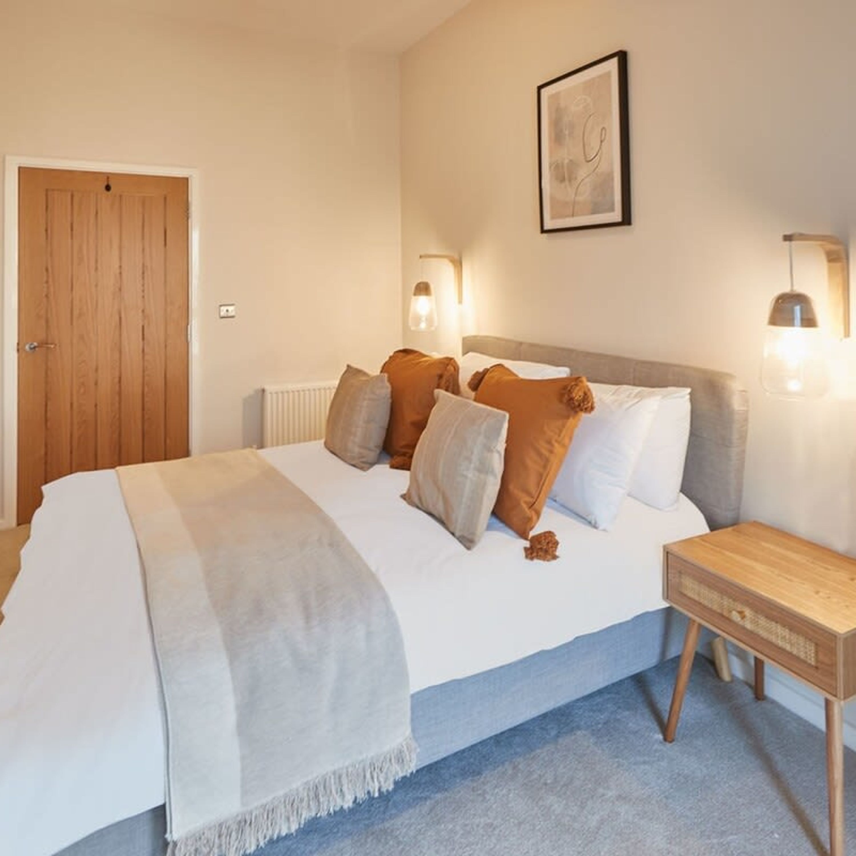 Ein Schlafzimmer mit einem Bett, einem Nachttisch aus Holz und zwei Wandleuchten.