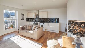 A spacious living area with a sofa, a dining table, and a kitchen in the background. - Host Stay Abbey Court Apartment (Whitby)