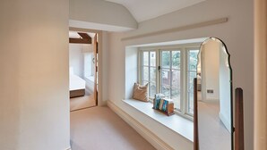 A hallway with a built-in bench, a mirror, and a window with a view of the outside. - Host Stay The Cobbles (Northallerton)