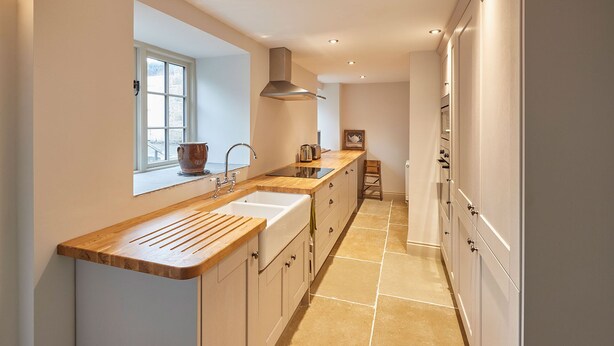 A narrow kitchen with a wooden countertop, a window, and a built-in oven. - Host Stay The Cobbles (Northallerton)