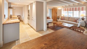 A modern kitchen with white cabinets and a wooden island, leading to a living area with a sofa and coffee table. - Host Stay The Cobbles (Northallerton)