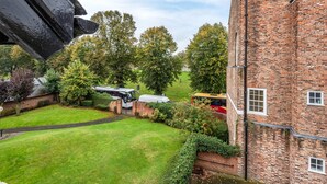 A courtyard with a brick building, a lawn, and parked buses. - Host Stay Feversham House (York)