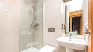 A modern bathroom with a glass shower enclosure, a white toilet, and a sink with a mirror. - Host Stay Feversham House (York)