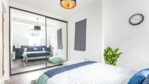 A modern bedroom with a large bed, a mirror, a clock, and a potted plant. - Host Stay Feversham House (York)
