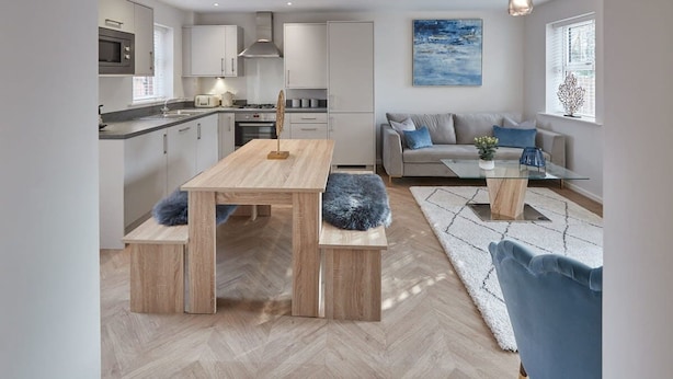 A modern kitchen with a dining area, a sofa, and a coffee table.
