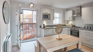 A modern kitchen with white cabinets, a microwave, a stove, and a dining area with a wooden table and bench.