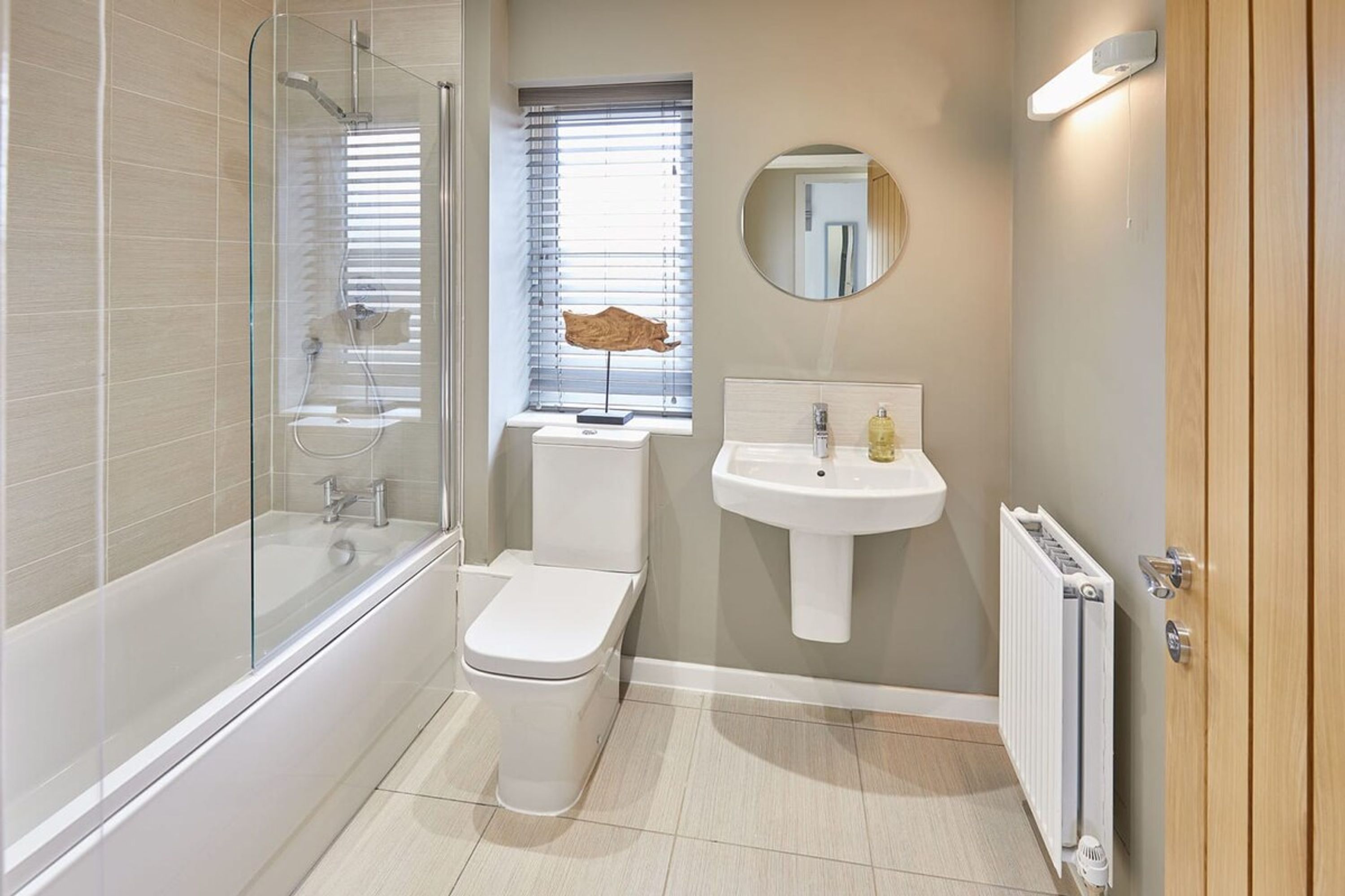 A modern bathroom with a glass-enclosed shower, a toilet, a sink, and a radiator.
