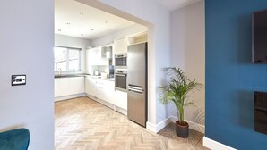 Une cuisine moderne avec des armoires blanches, des appareils en acier inoxydable et un parquet en bois disposé en chevrons.
