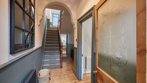 Ein Flur mit einer Holztreppe, einem Heizkörper und einer Tür mit Milchglas.