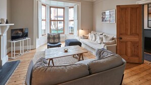 Ein gemütliches Wohnzimmer mit einer Couch, einem Couchtisch, einem Fernseher und einem Kamin.