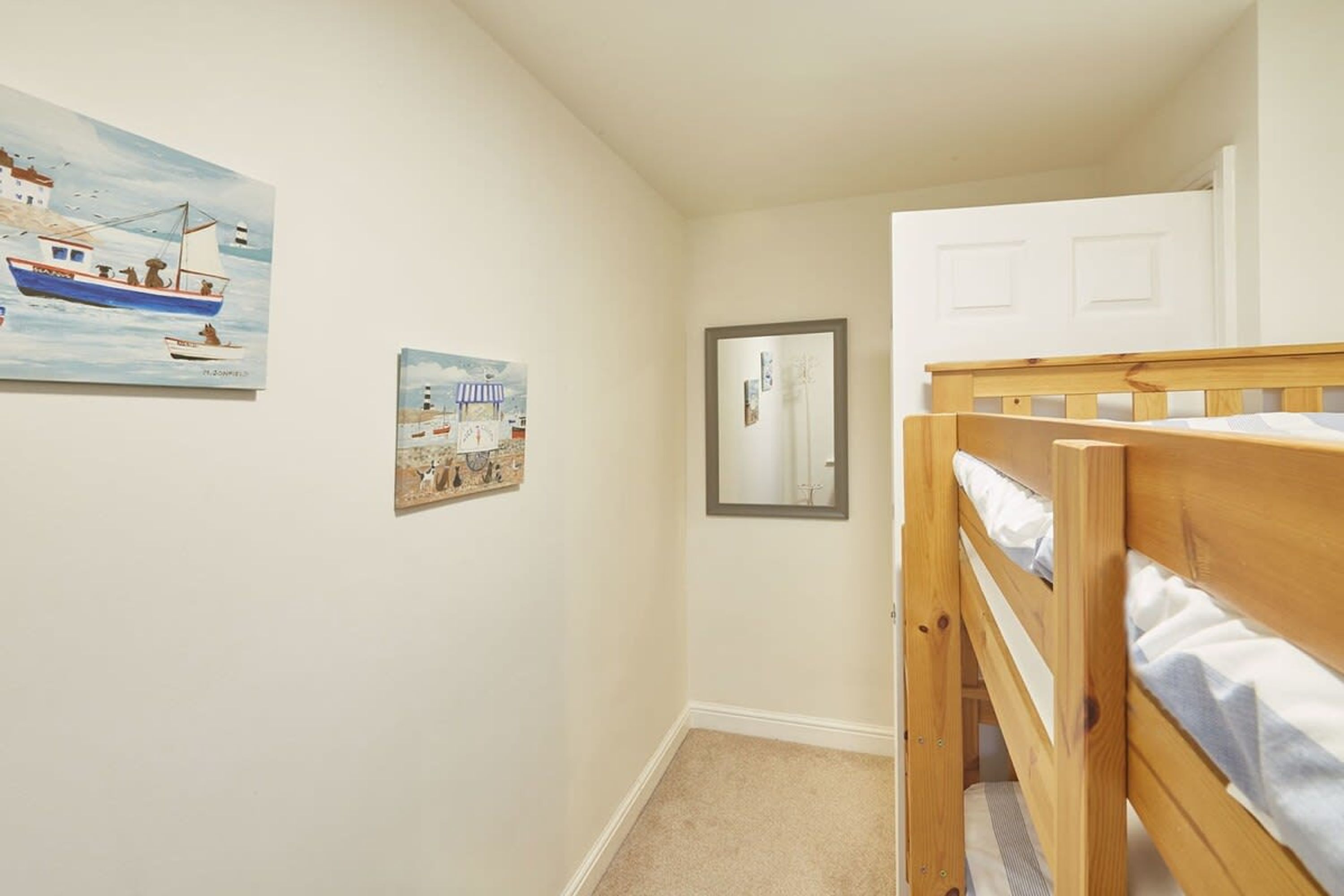 A bedroom with a bunk bed, a small framed picture, and a wall-mounted mirror.