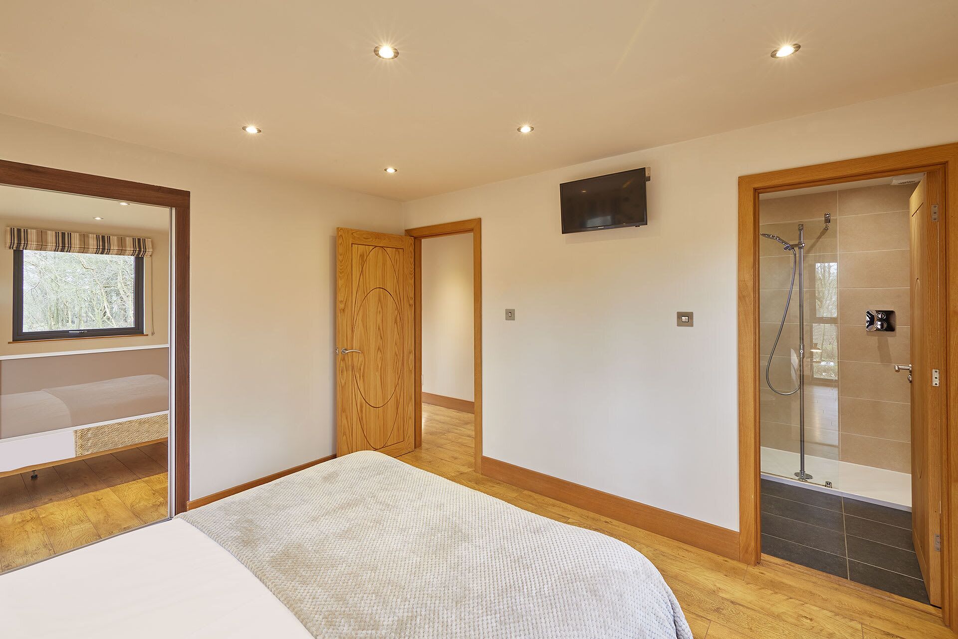Une chambre à coucher avec un lit, une télévision, une douche et une armoire en bois.