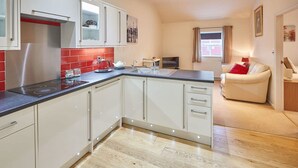Et moderne køkken med hvide skabe, en backsplash i røde fliser og en indbygget komfur.