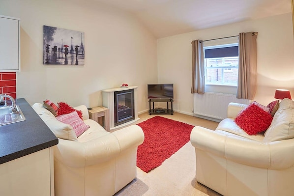 A living room with a fireplace, a TV, and a window with curtains.