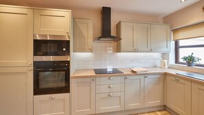 A modern kitchen with white cabinets, a built-in oven, a microwave, and a range hood. - Host Stay Wood Street Cottage (Barnard Castle)