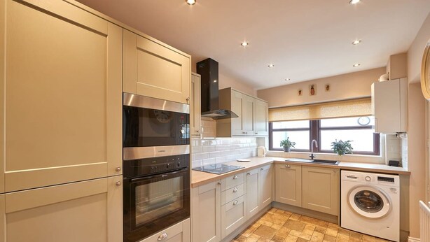 A modern kitchen with stainless steel appliances, beige cabinetry, and a built-in washing machine. - Host Stay Wood Street Cottage (Barnard Castle)