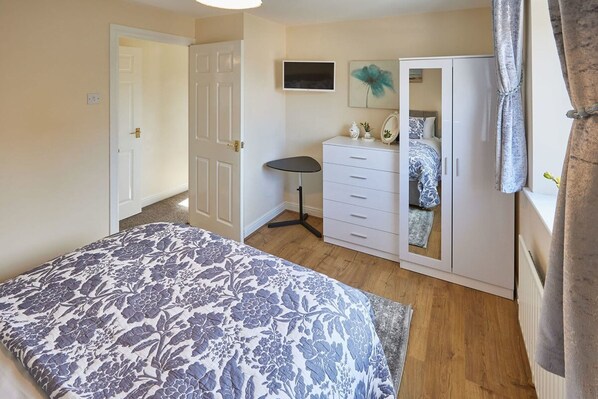 Un dormitorio con cama, cómoda, televisor y armario.